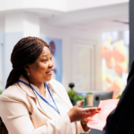 A woman is shown explaining a report to a man in a contemporary office hallway.