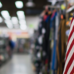 An American flag is wedged between product on a store shelf, reflecting a military discount.