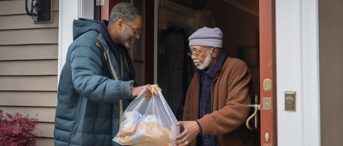 A young man delivers a food package to an elderly man as part of Meals on Wheels