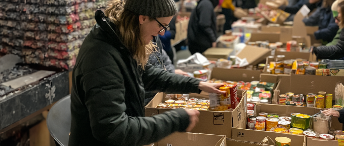 A woman sorts through the bins of a busy community food bank, thanks to TEFAP.